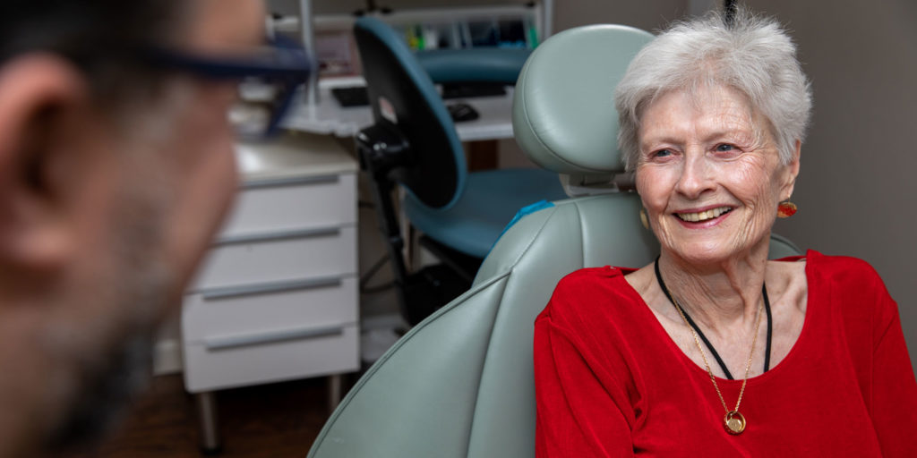 older patient with red top talking to dentist
